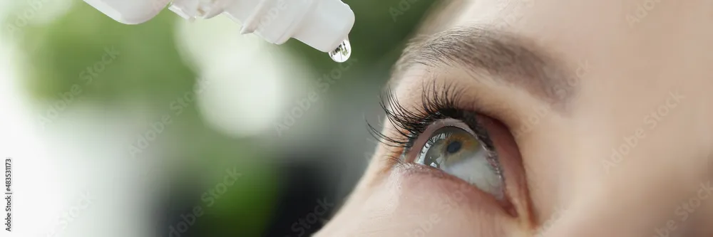 Close-up of a hazel eye with a dropper applying an Evolve eye drop