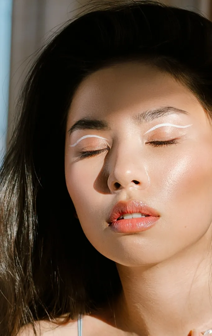 Woman with eyes closed wearing white graphic eyeliner